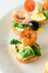 Close up of canape with wheat bread, greens and royal shrimp as an appetizer for party buffet or banquet isolated on white