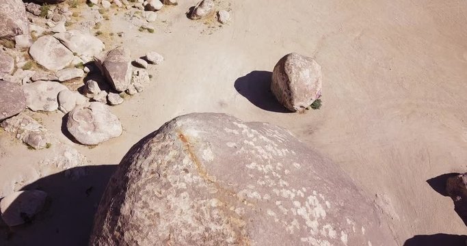 Largest Granite Boulder seven stories high compared to one car, Yucca Valley, California Desert,surrounded by smaller boulders, aerial drone shot