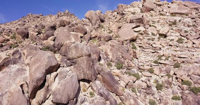 flying drone up to the Mojave Mountains  boulder rock formations pull up tilt down establishing shot