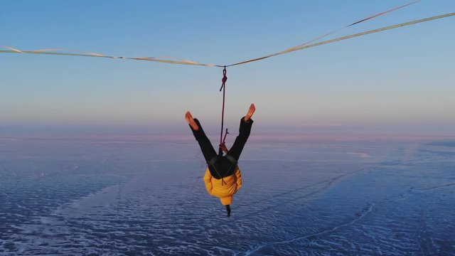 Young woman dancing standing on a tight sling at high altitude.