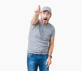 Handsome middle age hoary senior man wearing sport cap over isolated background Pointing with finger surprised ahead, open mouth amazed expression, something in front