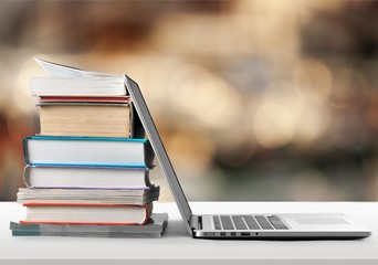 Stack of books with laptop on table