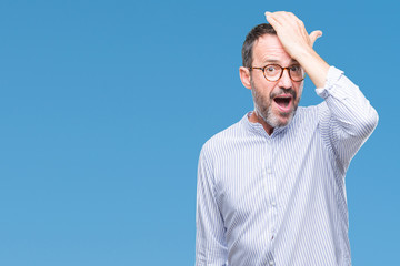 Middle age hoary senior man wearing glasses over isolated background surprised with hand on head...