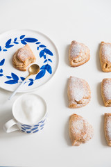 Delicious homemade dessert on blue plates. Shortbread sweet with coffee in a white mug. teaspoon golden. Saucer with earrings of leaves. On a white background.