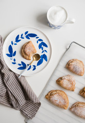 Delicious homemade dessert on blue plates. Shortbread sweet with coffee in a white mug. teaspoon golden. Saucer with earrings of leaves. On a white background.