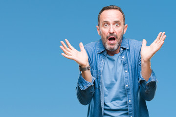 Fototapeta premium Middle age hoary senior man over isolated background clueless and confused expression with arms and hands raised. Doubt concept.