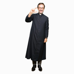 Middle age priest man wearing catholic robe smiling and confident gesturing with hand doing size...
