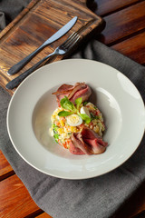 Top view of salad with thai style marbled beef with greens, crunchy cucumber, bell pepper and green peas, served in a fancy restaurant
