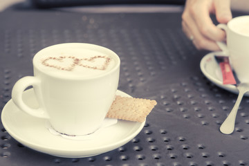 Love and coffee. Heart shape in a cup of delicious coffee. Romantic coffee concept in a pub, restaurant or cafe. Fashionable matte filter and shallow depth of field.