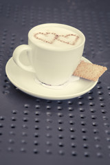 Love and coffee. Heart shape in a cup of delicious coffee. Romantic coffee concept in a pub, restaurant or cafe. Fashionable matte filter and shallow depth of field.