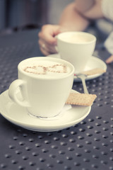 Love and coffee. Heart shape in a cup of delicious coffee. Romantic coffee concept in a pub, restaurant or cafe. Fashionable matte filter and shallow depth of field.