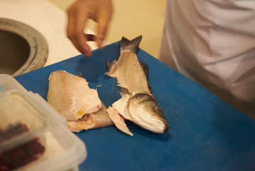The chef prepares fresh fish fillet. Man hands gutting fish, close-up