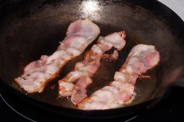Sizzling hot bacon in a cast iron skillet