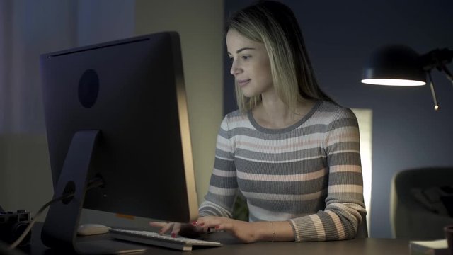 Happy young woman chatting online at night