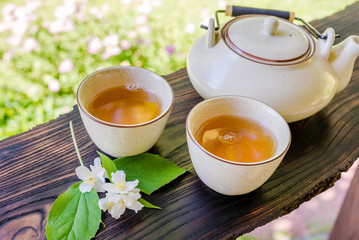 Two cups of tea and teapot on wooden table. Summertime