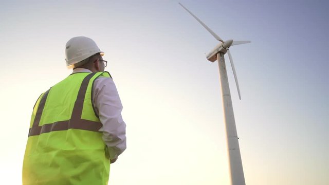 The engineer in uniform coming to windmill and starts to remove the camera on your tablet