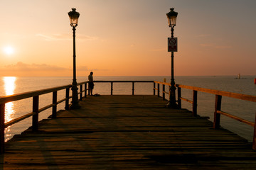 Wooden dock, sea and fisherman in the sunrise. Beautiful summer scenery