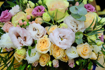 Bouquet of lilies and roses, close-up. Beautiful flowers with green leaves. Yellow and pink roses, dark red lilies.