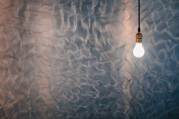 Single Light Bulb Hanging with aluminum Background, copy space.