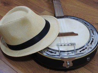 A samba banjo (a Brazilian string musical instrument) and a samba player (sambista) hat on a wooden surface. The instrument is widely used to accompany samba, the most popular Brazilian rhythm.
