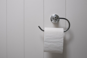 White toilet tissue against a white timber wall