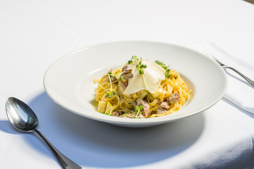 Tagliatelle pasta with cheese and chicken meat served on a white plate