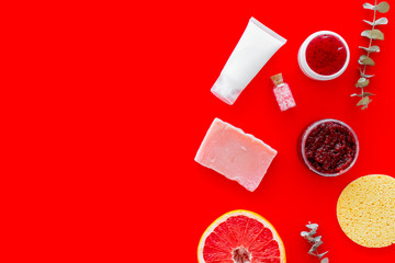 Organic cosmetics with herbs and grapefruit on red background top view mockup