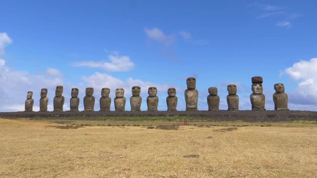Breathtaking shot of a row of fifteen famous moai statues under the clear blue summer sky on Easter Island. Spectacular ancient monoliths with human faces in Chile all facing the same direction.
