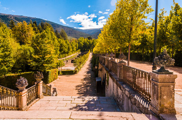 Stairs that lead to palatial building inside the farm of San Ildefonso in Segovia. Beautiful path surrounded by trees and gardens and in the background the mountains.
