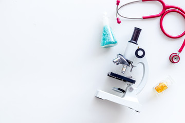 Do medical research with microscope, stethoscope, test-tubes in lab on white background top view mock-up