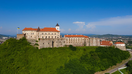 Picturesque view to the Palanok Castle with the red roofs under the blue sky in Mukachevo, Transcarpathian region in Ukraine. Horizontal outdoors shot.