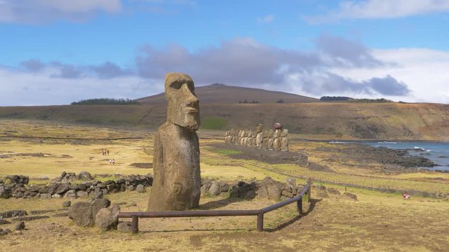 AERIAL, COPY SPACE: Flying around a large moai sculpture on a remote island in sunny Chile. Spectacular view of the untouched Easter Island with its world famous volcanic human shaped sculptures.
