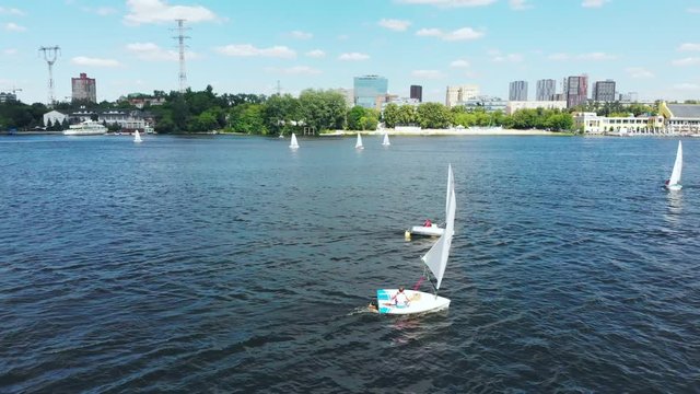 Beautiful panoramic view. Small sailing boats on the river, Competition. Regatta. Racing sailing sports courts. Training on small sailboats. Filming from the air. View from above.