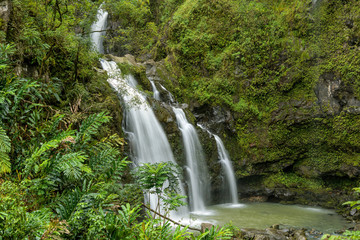 Fototapeta na wymiar Waterfalls in Rain-forest - A close-up view of a multi-tiered waterfall inside of a dense rain-forest at side of the Road to Hana Highway on a rainy afternoon, Maui, Hawaii, USA.