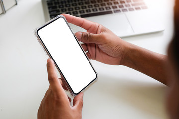 Cropped shot view of man hands holding smart phone with blank copy space screen for your text message or information content, female reading text message on cell telephone during in urban setting. 