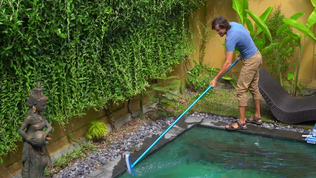 Young man professional swimming pool cleaner does pool cleaning service