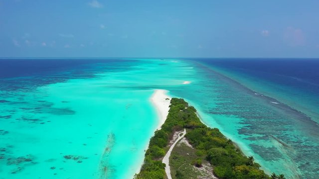 tropical island in Philippine Sea with coconut palms, with crystal clear water showing corals on seafloor aerial drone wide dolly in shot