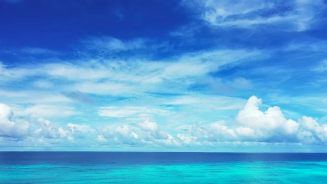 astonishing horizon view, endless open ocean meeting beautiful blue sky with fantastic cloud formation, aerial drone pedestal down shot