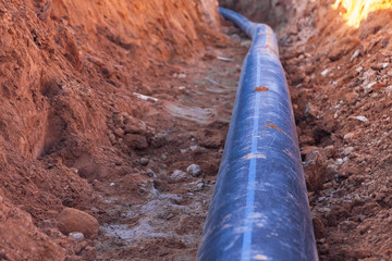 A black plastic pipe with a blue strip to feed water to the house