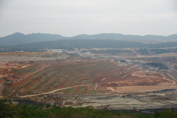 Obraz premium Lignite coal mining industry as a raw materials for coal fire electric power plant. There are excavators and transport trucks are working within the lignite coal mine.
