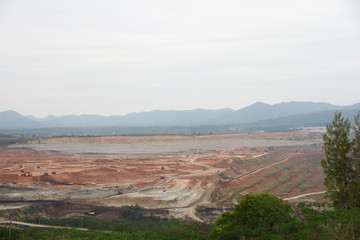 Lignite coal mining industry as a raw materials for coal fire electric power plant. There are excavators and transport trucks are working within the lignite coal mine.