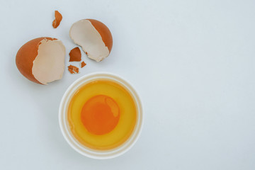 White egg and egg yolk on Light gray background, top view. With copy area