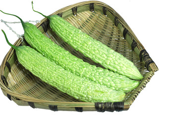close up on bitter melons in bamboo sieve isolated on white background