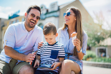 Smiling parents and little boy with tablet pc outdoor