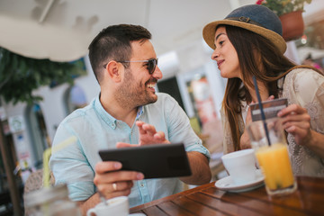 Happy young couple shopping online while sitting in a cafe.