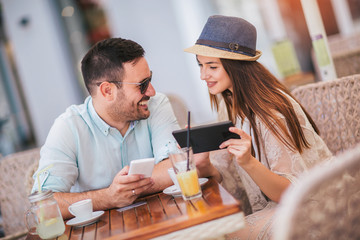 Cute couple looking at a tablet at the cafe terrace