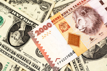 A close up image of a two thousand Tanzanian shilling bank note on a background of American one...