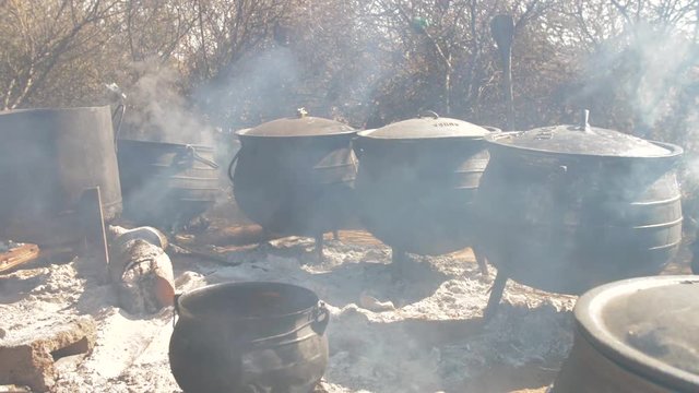 Traditional Botswana food being cooked outside in large three legged pots