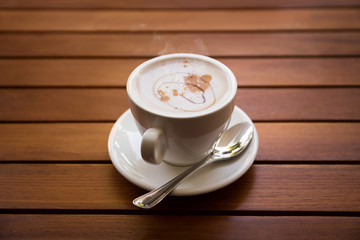 Cup of coffee with spoon on wooden table