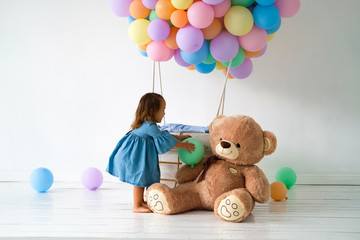 A little girl is celebrating her birthday. Big Teddy bear in a birthday present.